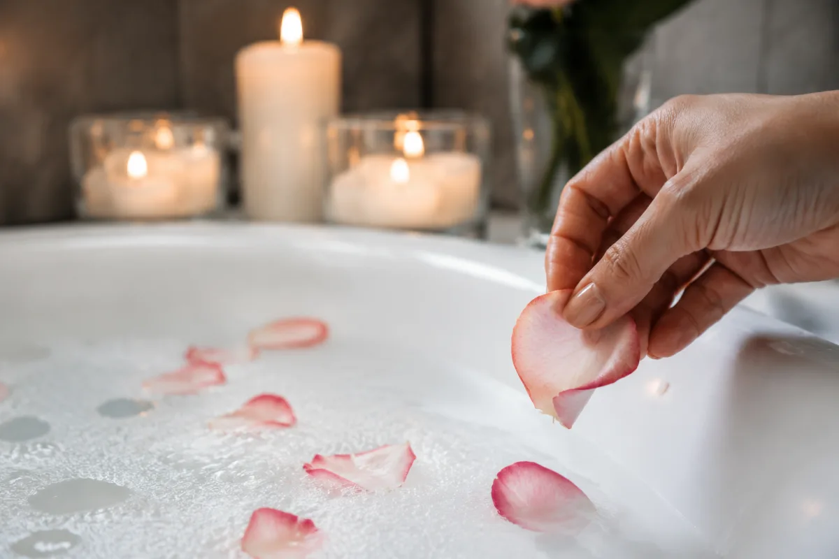 Faire un bain sensuel : éveillez vos 5 sens pour une soirée inoubliable Gros plan sur un verre de champagne posé au bord d'une baignoire avec des bulles de bain mousseuses