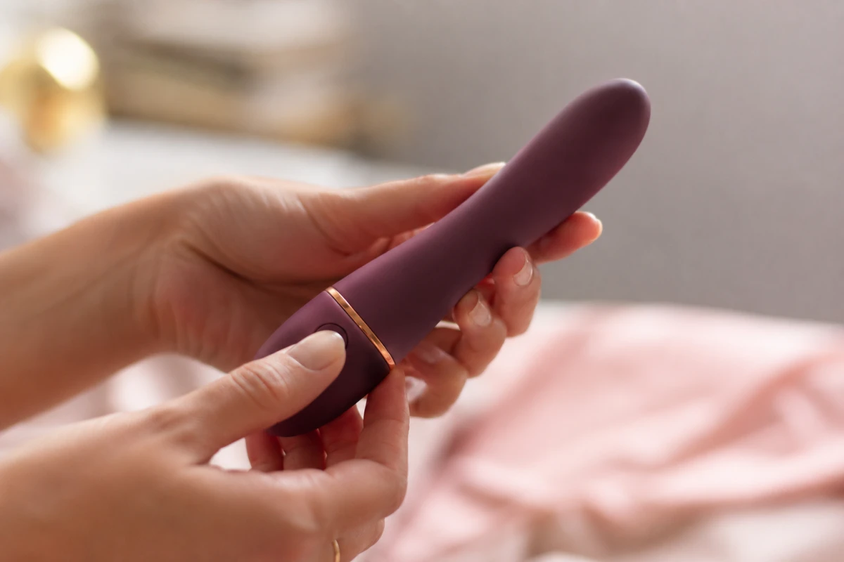 Utiliser un vibromasseur : le guide honnête pour bien démarrer Main tenant un petit vibromasseur galet montrant les boutons de réglage d'intensité en gros plan